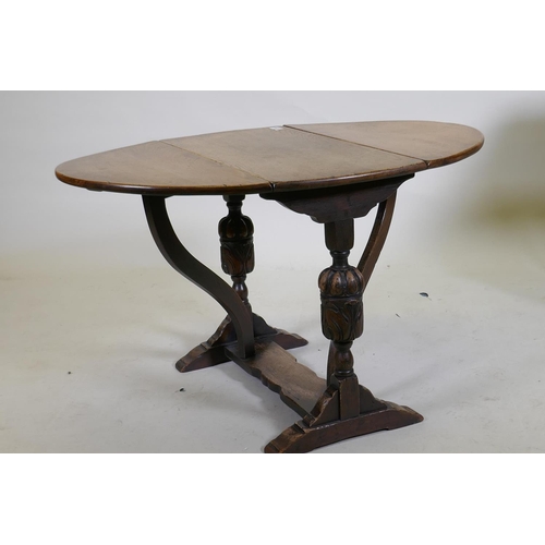 1056 - An oak drop leaf occasional table, raised on carved end supports united by a shaped stretcher, 68 x ... 