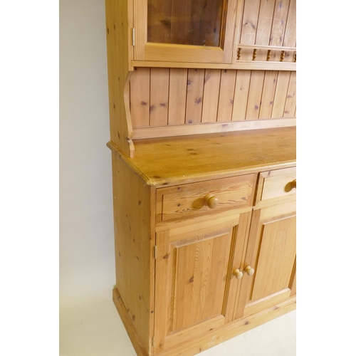 1061 - A pine dresser, the upper section with two glazed door flanking open shelves, the base with four dra... 