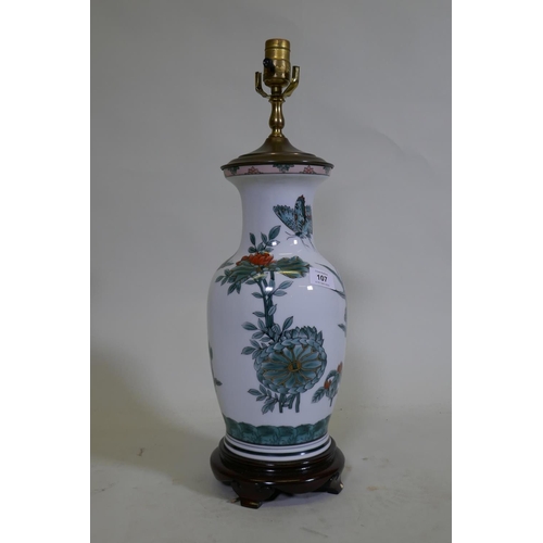 107 - A porcelain table lamp with butterfly and lotus flower decoration in the Chinese manner, 57cm high