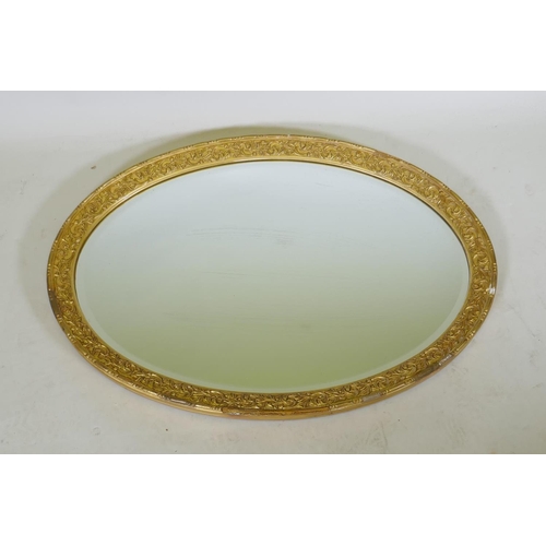 1070 - A gilt composition oval wall mirror, 59 x 86cm