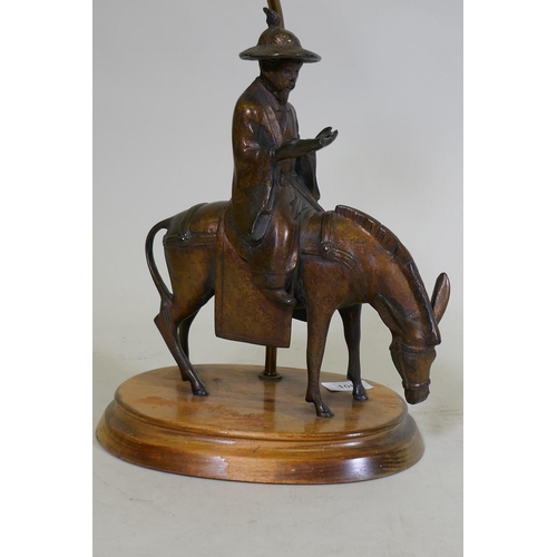 108 - A vintage table lamp in the form of an oriental gentleman riding a mule, mounted on a wood base, 63c... 