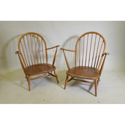 1081 - A pair of mid century Ercol beechwood hoopback elbow chairs with solid seats, 83cm