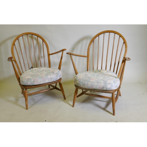 1081 - A pair of mid century Ercol beechwood hoopback elbow chairs with solid seats, 83cm