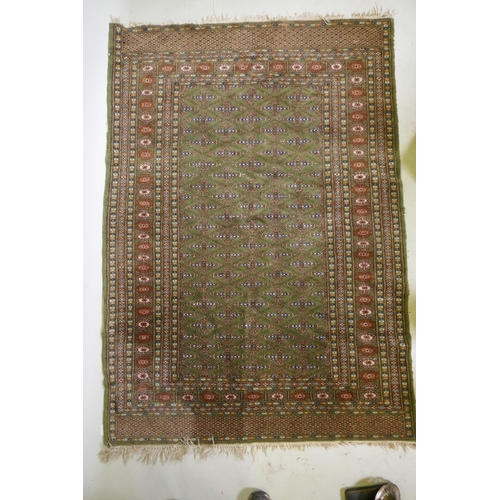 1087 - A fine woven green ground Turkish rug with an allover Bokharra style design, 130 x 182cm