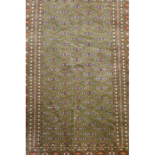 1087 - A fine woven green ground Turkish rug with an allover Bokharra style design, 130 x 182cm