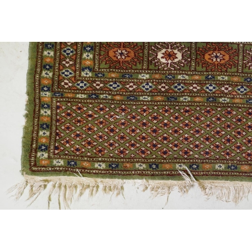 1087 - A fine woven green ground Turkish rug with an allover Bokharra style design, 130 x 182cm