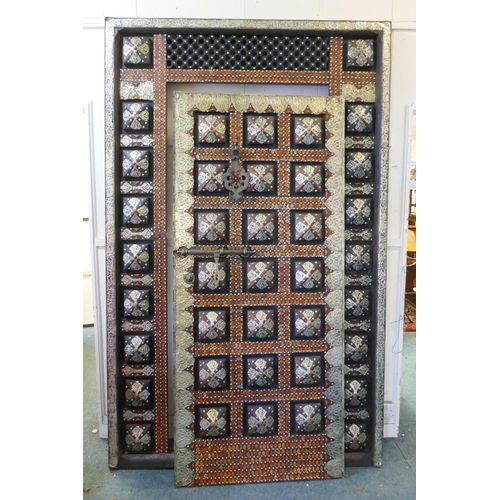 1089 - A large oriental door in frame with white metal decorative mounts and inset with amber style shards,... 