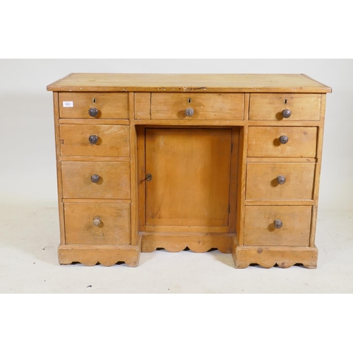 1091 - A C19th pine nine drawer kneehole desk with central cupboard raised on a shaped plinth base, 110 x 5... 