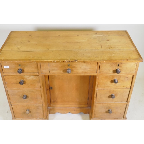 1091 - A C19th pine nine drawer kneehole desk with central cupboard raised on a shaped plinth base, 110 x 5... 