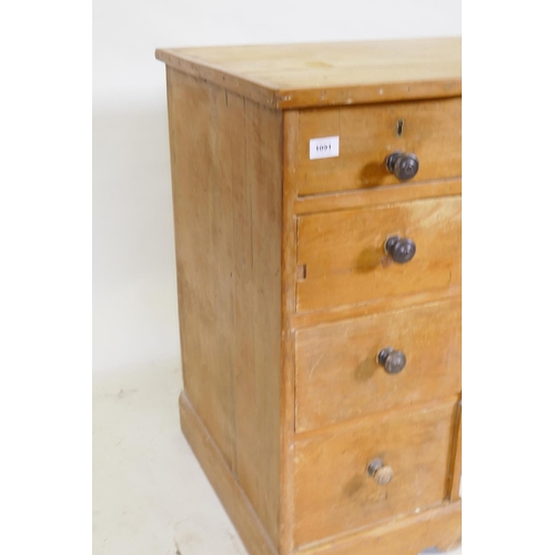 1091 - A C19th pine nine drawer kneehole desk with central cupboard raised on a shaped plinth base, 110 x 5... 