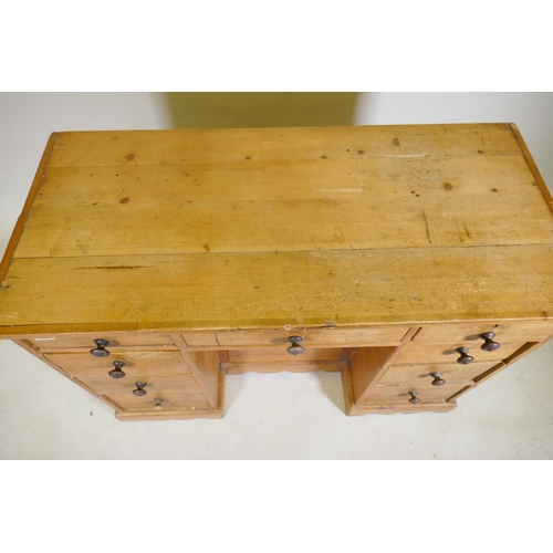 1091 - A C19th pine nine drawer kneehole desk with central cupboard raised on a shaped plinth base, 110 x 5... 