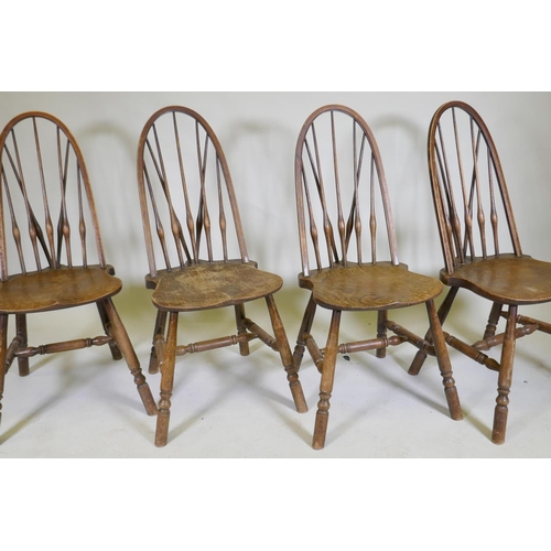 1100 - A set of four hoop back Windsor chairs with high backs and shaped solid elm seats, raised on turned ... 