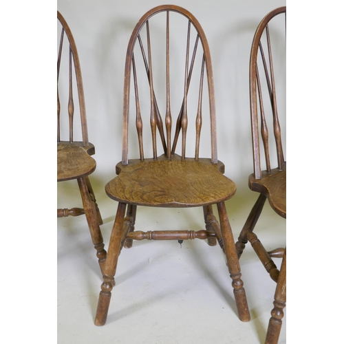 1100 - A set of four hoop back Windsor chairs with high backs and shaped solid elm seats, raised on turned ... 