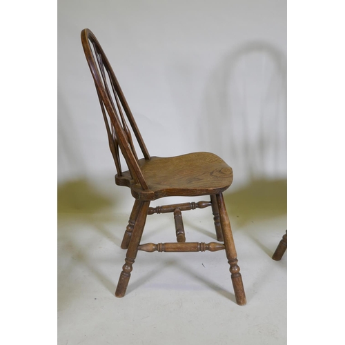 1100 - A set of four hoop back Windsor chairs with high backs and shaped solid elm seats, raised on turned ... 