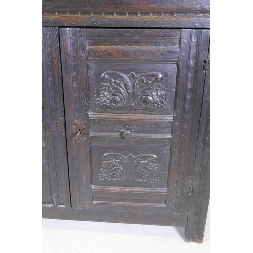 1108 - An C18th continental bog oak dresser/buffet with three cupboards and fielded carved panels with Gree... 