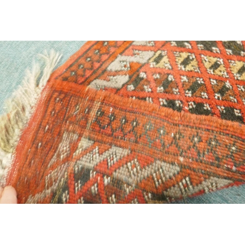 1109 - A small hand woven wool village runner with trellis design on a red ground, 140 x 50cm