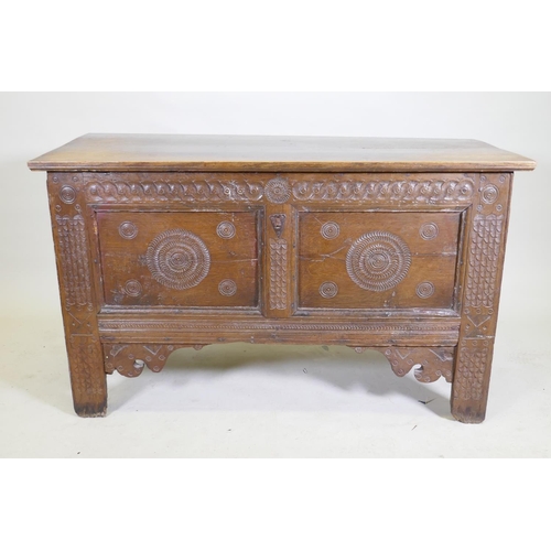 1114 - An C18th continental oak coffer, two panelled front with chip carved decoration under a sea scroll f... 