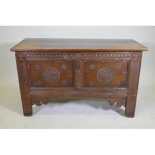 1114 - An C18th continental oak coffer, two panelled front with chip carved decoration under a sea scroll f... 