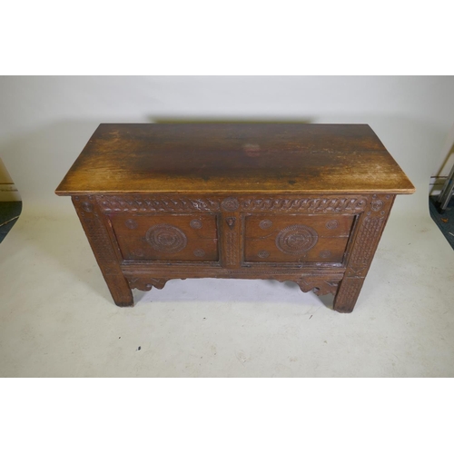 1114 - An C18th continental oak coffer, two panelled front with chip carved decoration under a sea scroll f... 