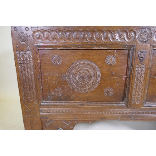 1114 - An C18th continental oak coffer, two panelled front with chip carved decoration under a sea scroll f... 