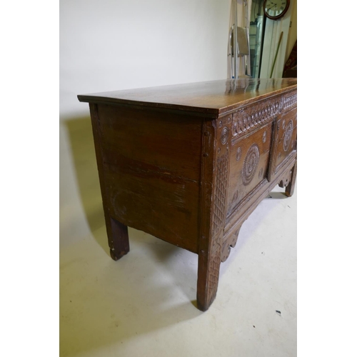 1114 - An C18th continental oak coffer, two panelled front with chip carved decoration under a sea scroll f... 