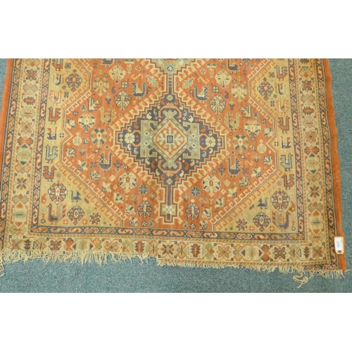 1125 - A Middle Eastern wool carpet with medallion design on a faded terracotta field, 160 x 110cm