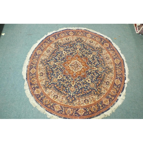 1126 - A wool carpet with Persian style designs on a red field with blue borders, 180cm diameter