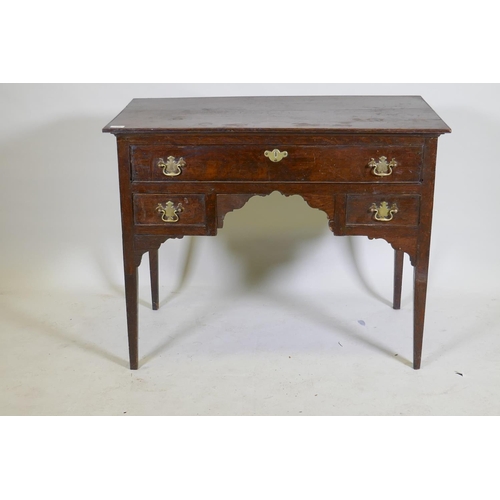 1129 - An C18th oak lowboy with long drawer over two small, with brass plate handles, raised on square tape... 