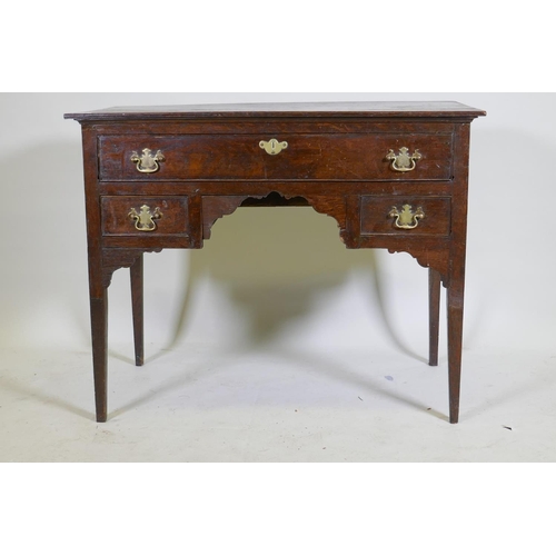 1129 - An C18th oak lowboy with long drawer over two small, with brass plate handles, raised on square tape... 