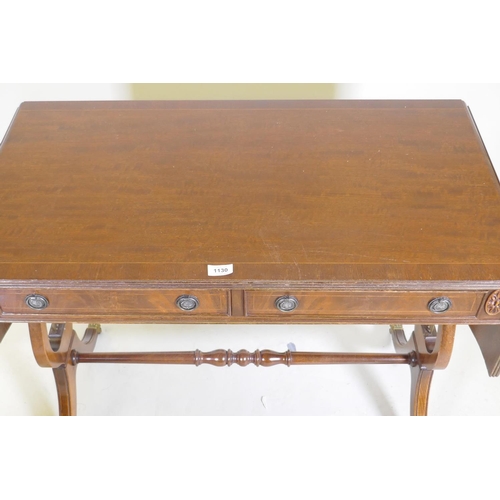 1130 - An inlaid mahogany Regency style sofa table with two drawers, raised on lyre shaped end supports, an... 