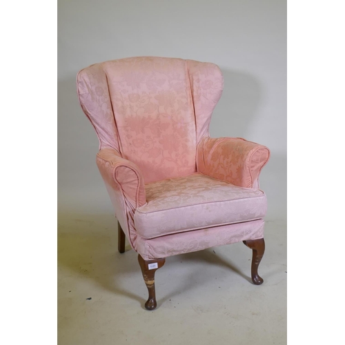 1131 - A wing back armchair, raised on cabriole supports