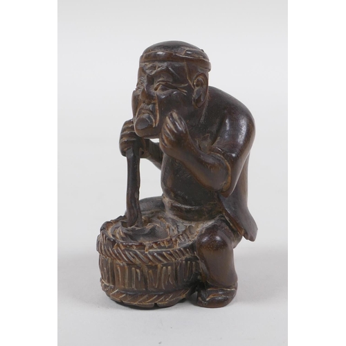 131 - A Japanese carved wood netsuke in the form of a man making mochi, 5cm high