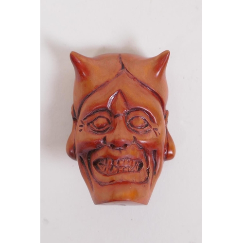 134 - A Japanese carved boxwood netsuke in the form of an oni mask, and another carved in the form of a sa... 