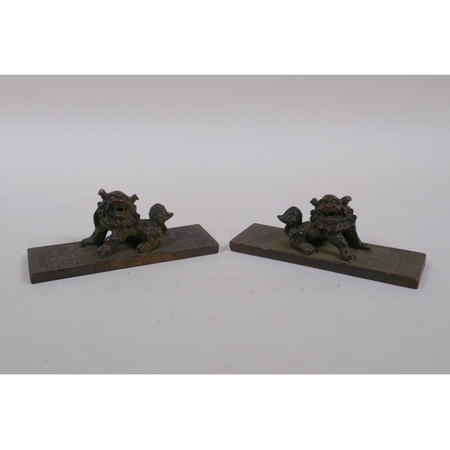 140 - A pair of Chinese bronze scroll weights with decorative characters and fo dog mounts, 4 x 11cm