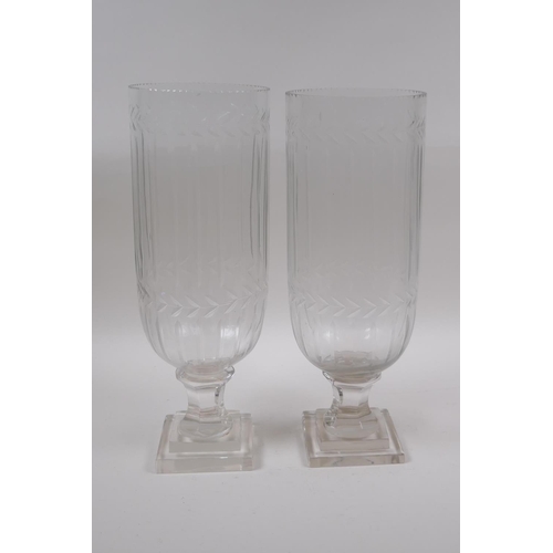 142 - A pair of glass hurricane vases with cut glass decoration, 34cm high, 12cm high