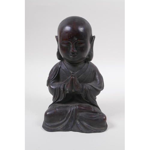 165 - A Chinese bronze figure of a buddha with oversized head, at prayer, 20cm high