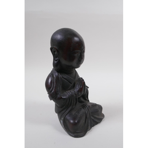 165 - A Chinese bronze figure of a buddha with oversized head, at prayer, 20cm high