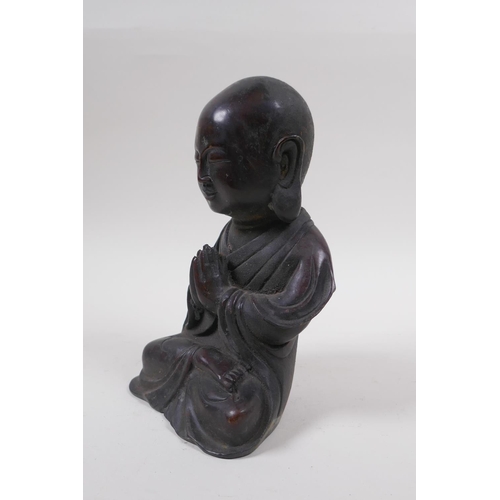 165 - A Chinese bronze figure of a buddha with oversized head, at prayer, 20cm high