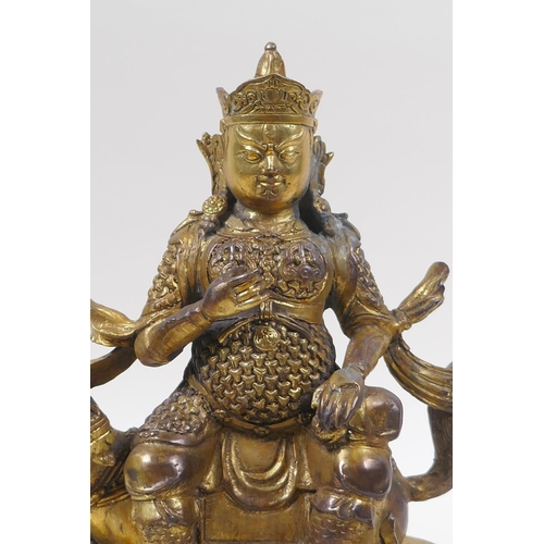 193 - A Sino Tibetan gilt bronze figure of an armoured deity, seated on a kylin, 22cm high