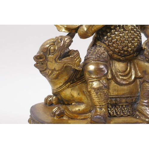 193 - A Sino Tibetan gilt bronze figure of an armoured deity, seated on a kylin, 22cm high