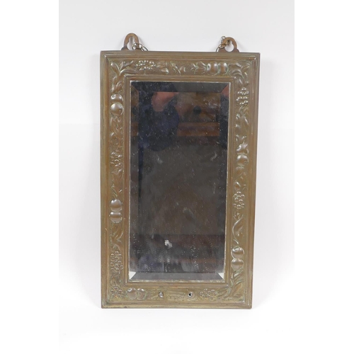 204 - An Arts and Crafts brass wall mirror with repousse fruit and flower decoration, 23 x 38cm