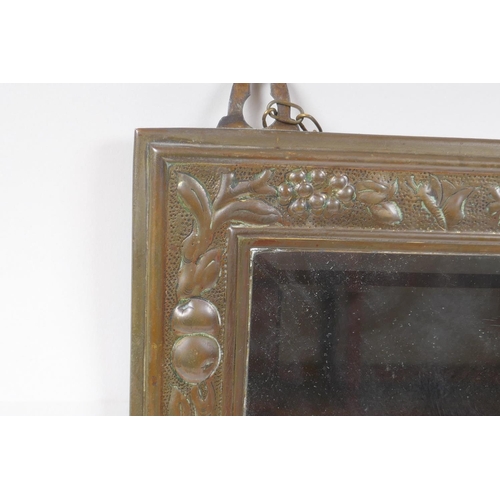 204 - An Arts and Crafts brass wall mirror with repousse fruit and flower decoration, 23 x 38cm