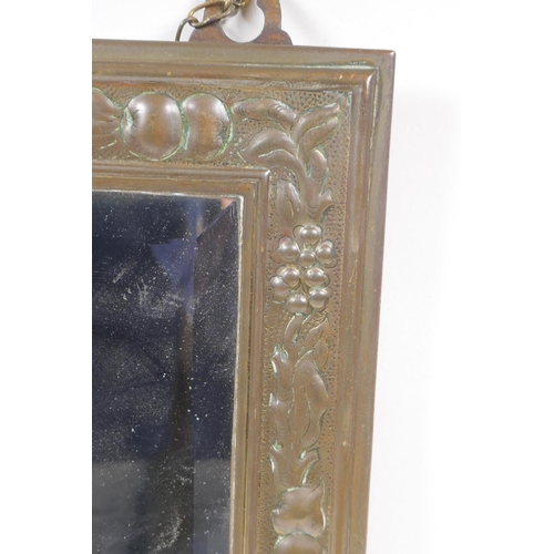 204 - An Arts and Crafts brass wall mirror with repousse fruit and flower decoration, 23 x 38cm