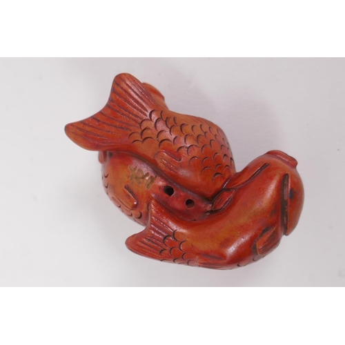 255 - A Japanese carved boxwood netsuke in the form of three carp, and another in the form of a barrel wit... 