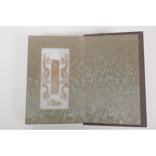 51 - A Chinese wood and silk bound book containing white jade tablets with chased and gilt character insc... 