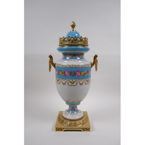 54 - A Sevres style continental porcelain urn with brass mounts, handles and base, with floral bouquet an... 