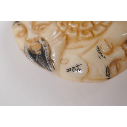 57 - A Japanese bone netsuke with carved mask decoration, signed, 4cm diameter