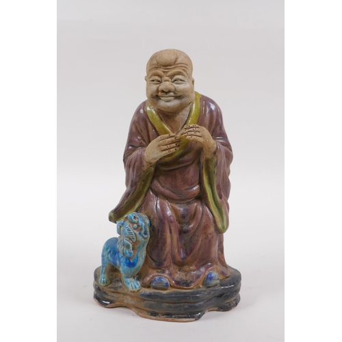 78 - A sancai glazed porcelain figure of Lohan and a fo dog, 21cm high