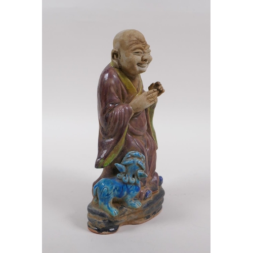 78 - A sancai glazed porcelain figure of Lohan and a fo dog, 21cm high