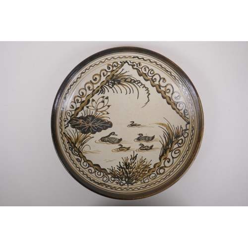 88 - A Chinese Cizhou kiln charger decorated with waterfowl upon a lotus flower pond, character inscripti... 